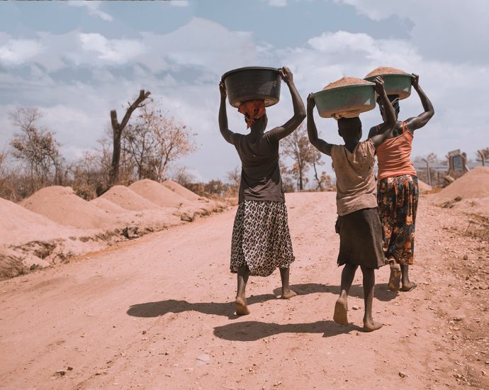 three women carrying basin while walking barefoot