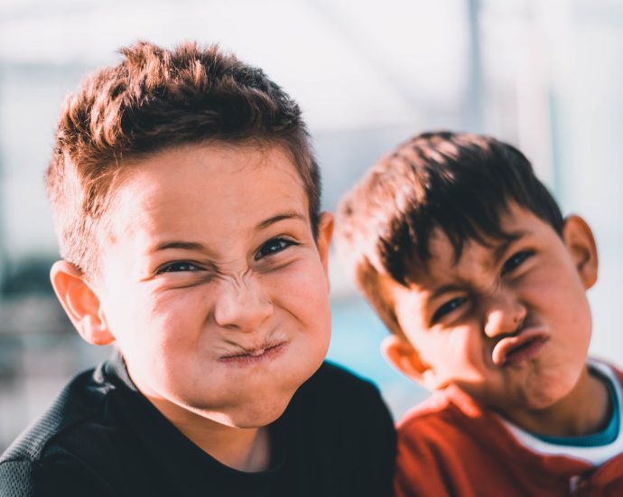 shallow focus photography of two boys doing wacky faces