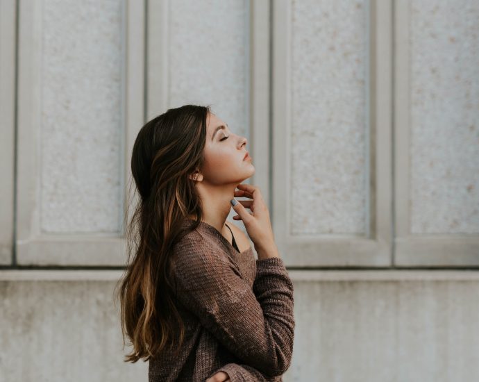 woman in brown long-sleeved top standing beside wall