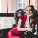 woman in black sleeveless dress sitting on black leather couch