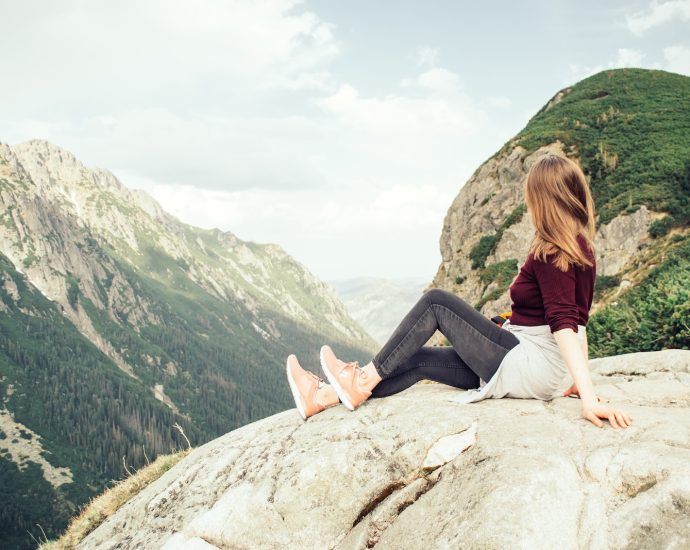 woman sitting on mountains peak