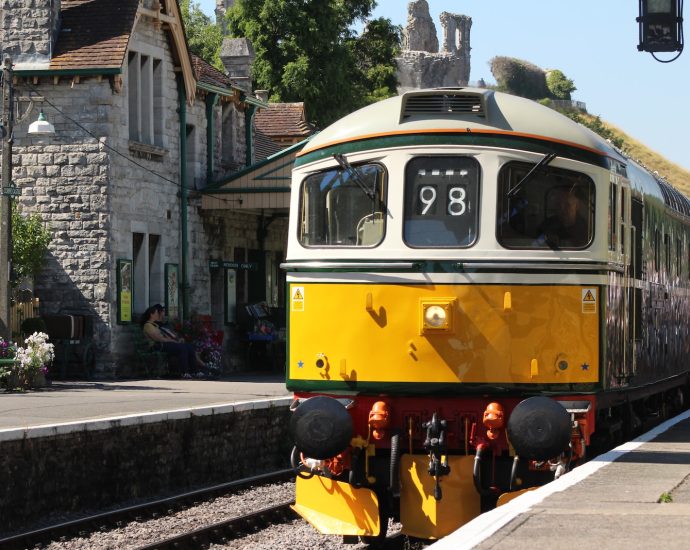 a yellow and green train pulling into a train station