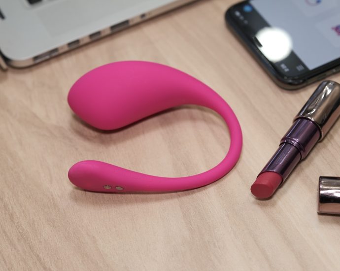 a table with a cell phone, lipstick, and a laptop