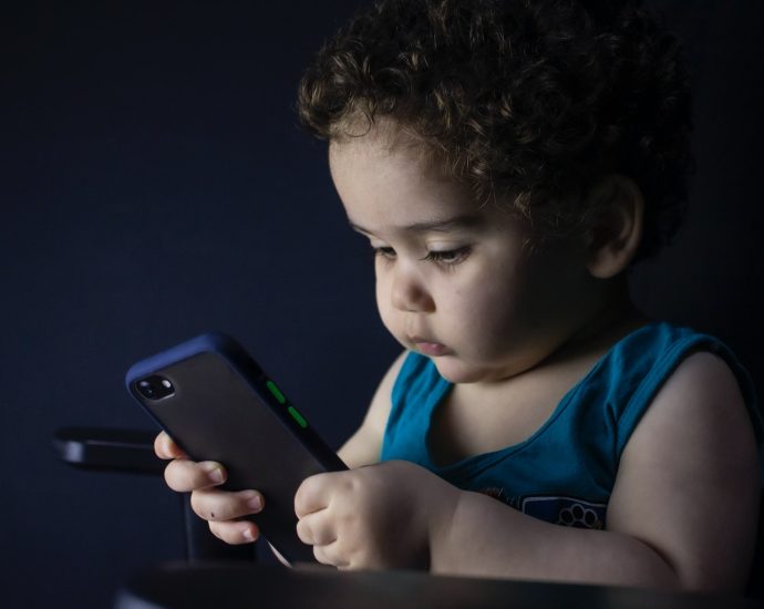 boy in blue tank top holding black iphone 5