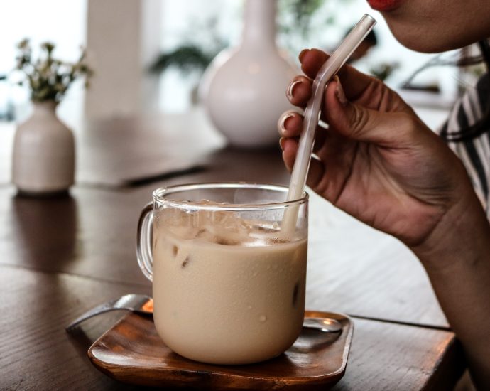 person holding clear drinking glass with milk