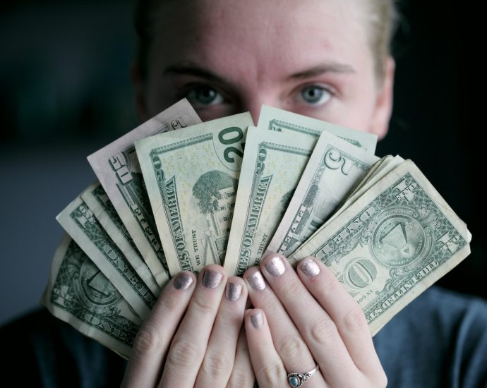 person holding fan of U.S. dollars banknote