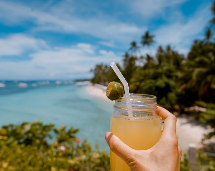 person holding mason jar with filled with juice at daytime