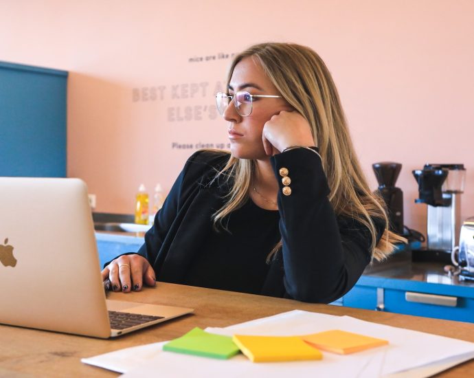 woman in black long sleeve shirt wearing black framed eyeglasses using macbook