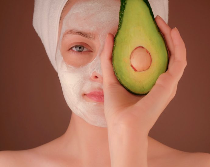 woman with white face mask holding green fruit