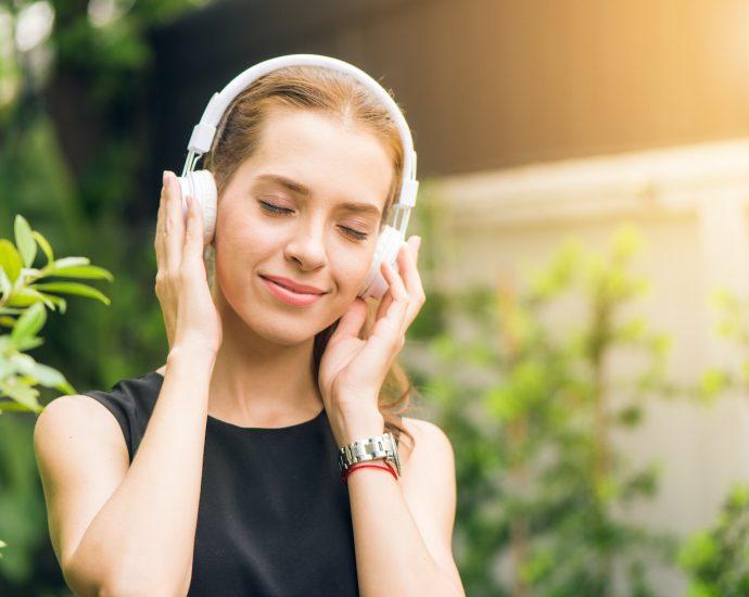 Woman Wearing Black Sleeveless Dress Holding White Headphone at Daytime