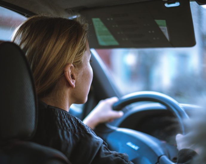 a woman sitting in a car with a steering wheel