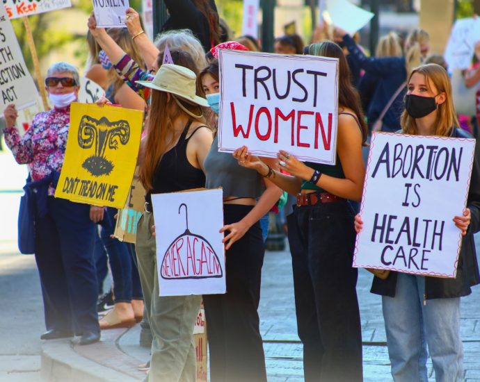 a group of women holding signs and wearing masks