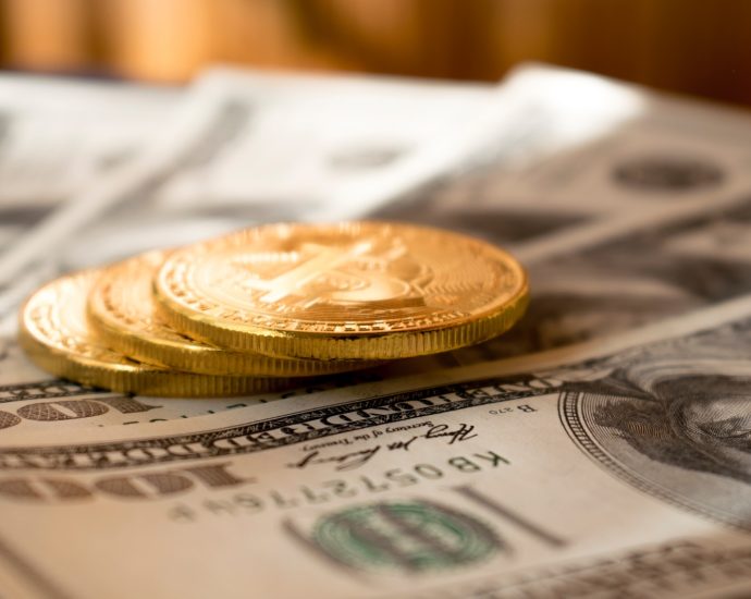 three round gold-colored coins on 100 US dollar banknotes