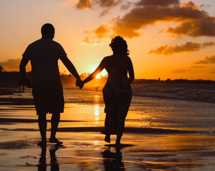 couple standing on body of water during golden hour