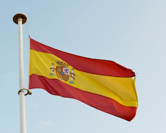 the spanish flag is flying high in the sky