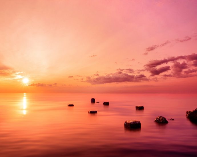 silhouette of rocks on sea during sunset