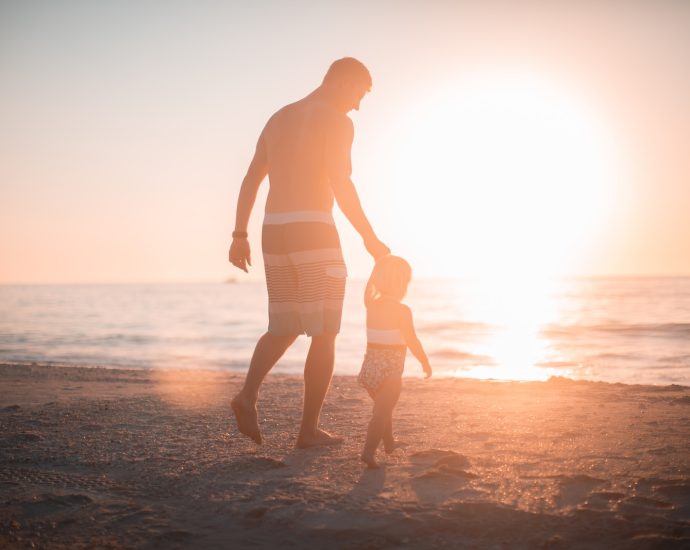 man holding girl heading towards sea