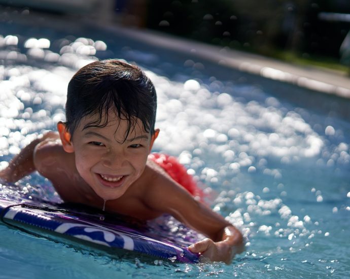 boy in pool smiling during daytime