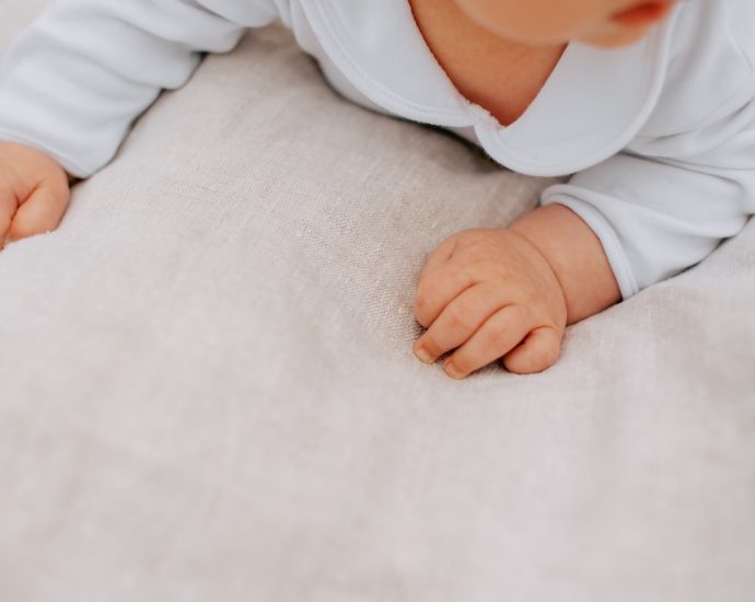 a baby laying on its back on a bed