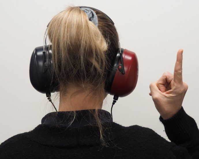 a woman wearing headphones pointing to the side