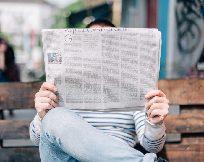 man sitting on bench reading newspaper