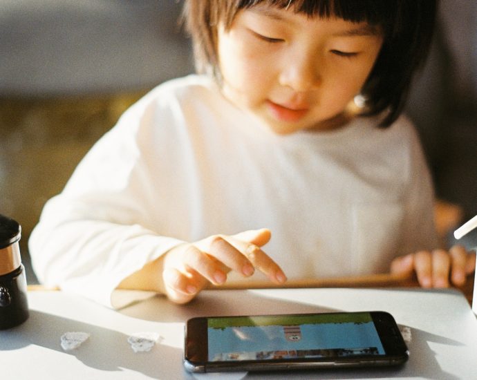 woman in white long sleeve shirt holding black smartphone