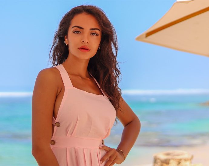 woman in pink spaghetti strap top standing on beach during daytime