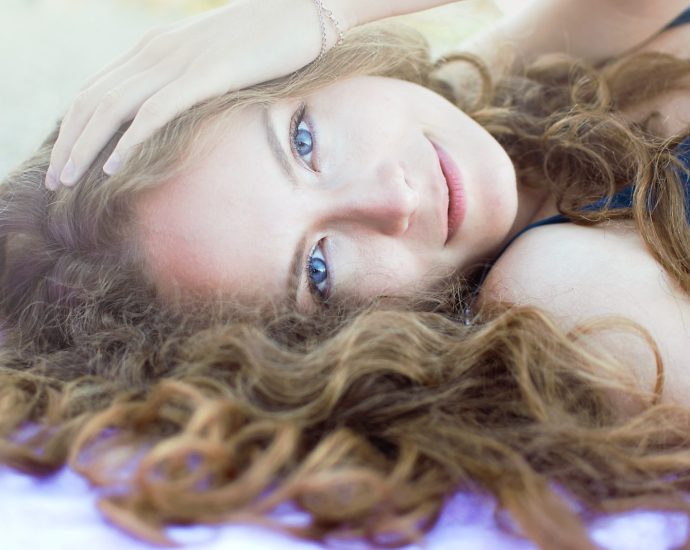 woman in purple tank top lying on blue textile