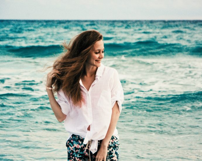 woman in white dress shirt standing on beach during daytime