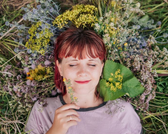 woman in gray crew neck shirt lying on green grass