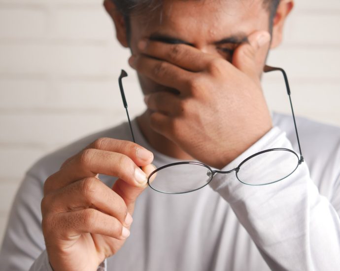 a man holding a pair of glasses up to his face