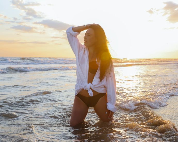 a woman is standing in the water at the beach