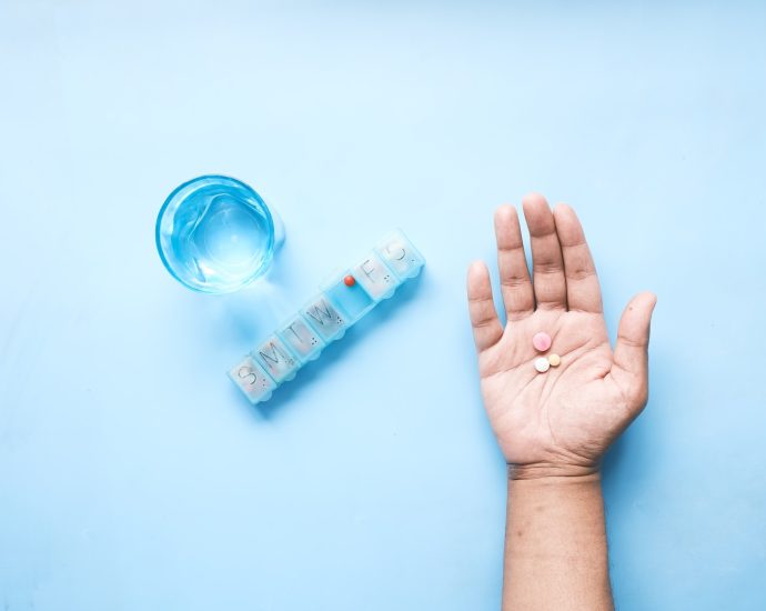 person holding pink and white medicine pill