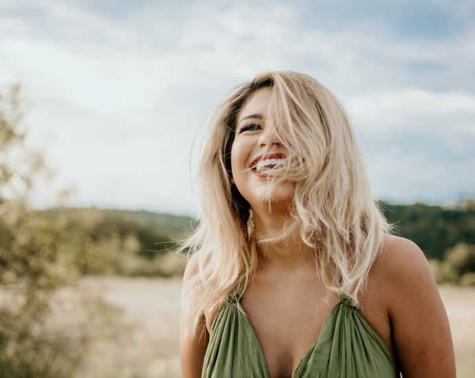 time-lapse photography of laughing woman with hair covering half of her face