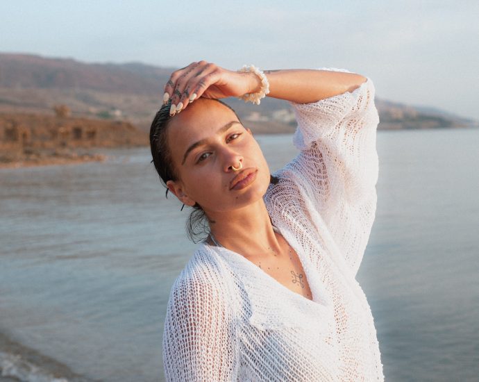 a woman standing on a beach next to a body of water