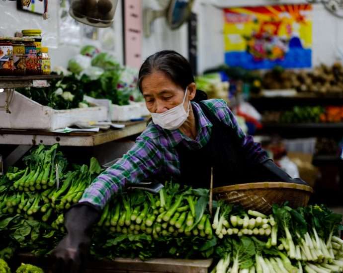 woman in black jacket holding green vegetable