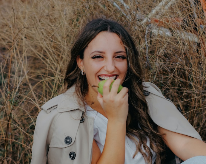 a woman sitting on the ground eating an apple