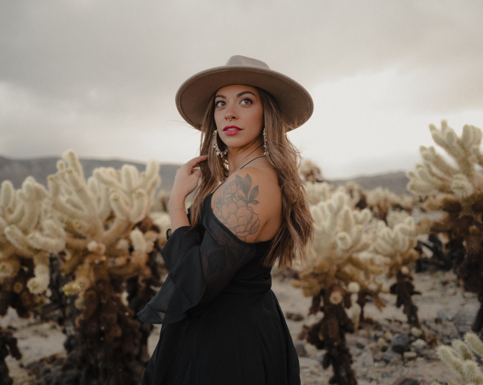 a woman wearing a hat standing in a field of cacti