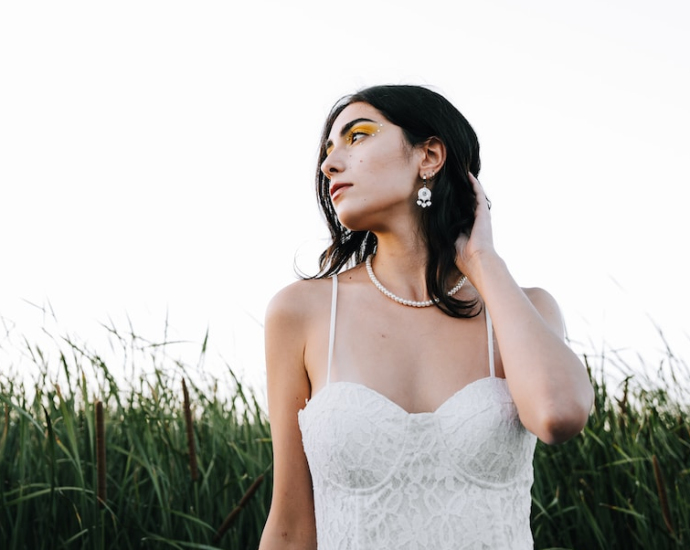 a woman in a white dress standing in tall grass