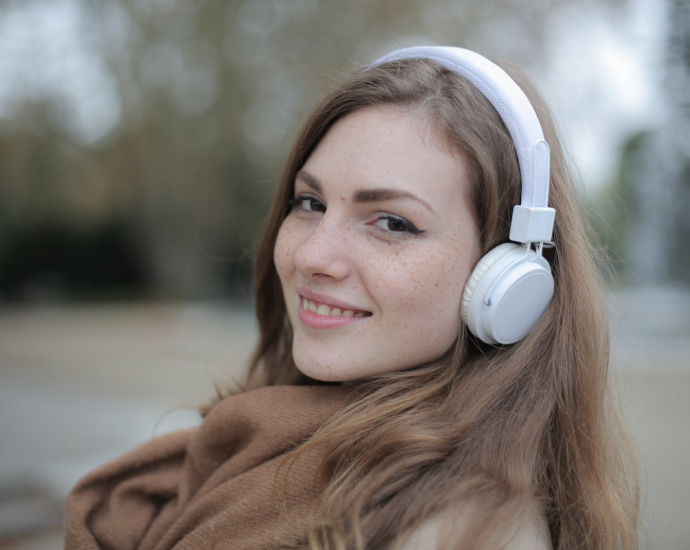 Joyful millennial woman in headphones listening to music in park