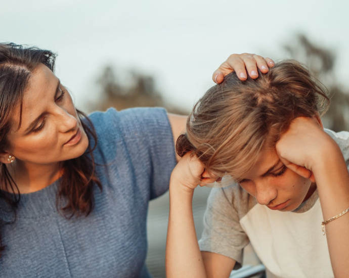 Woman in Blue Shirt Talking to a Young Man in White Shirt