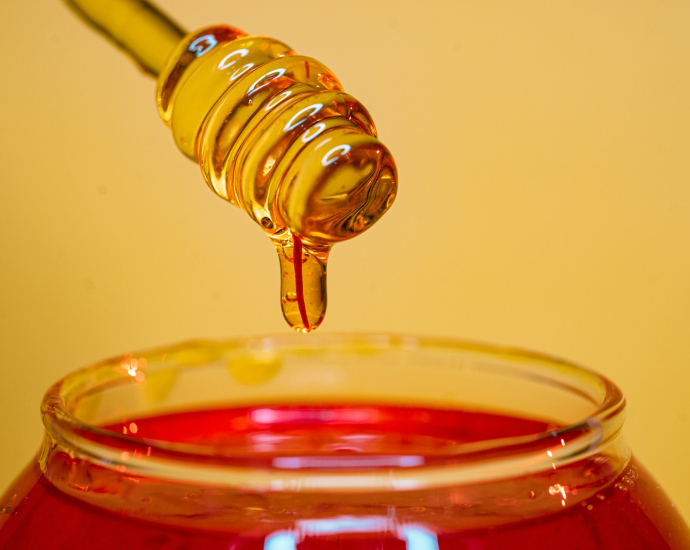 clear glass bottle pouring red liquid on clear drinking glass