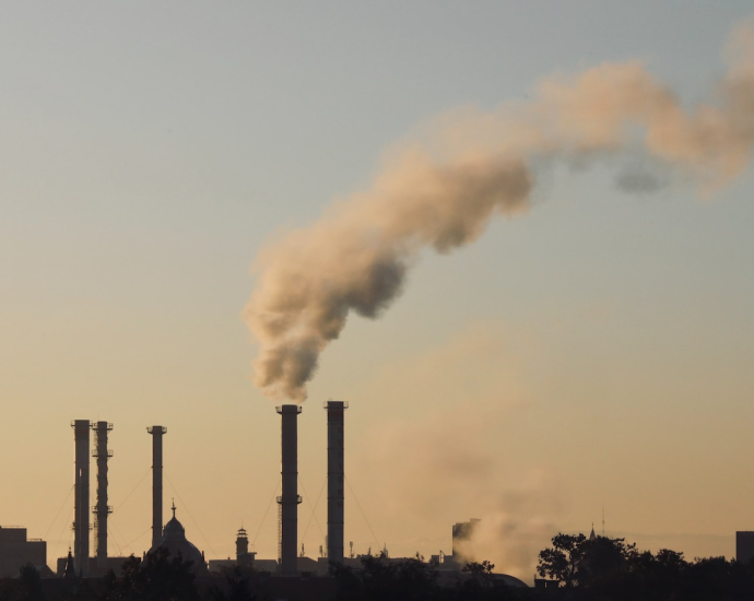 a smokestack emits from a factory in the distance