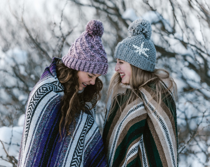 two women in multicolored striped blanket standing near tree