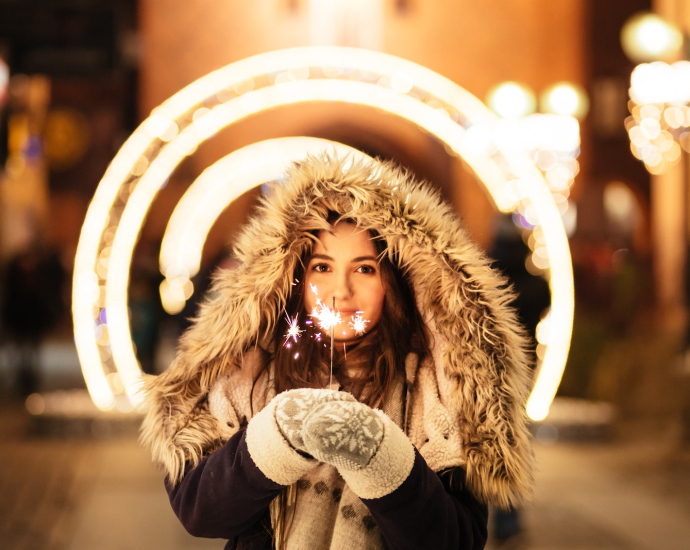 woman wearing coat and holding fireworks