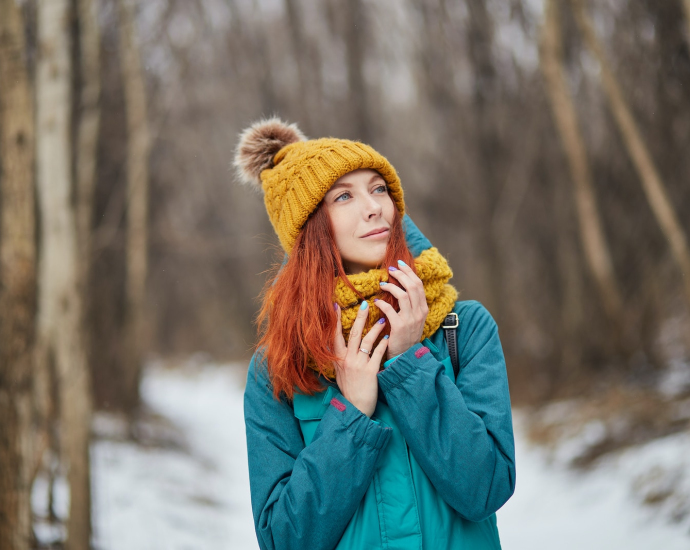 woman in blue jacket and brown knit cap standing on snow covered ground during daytime