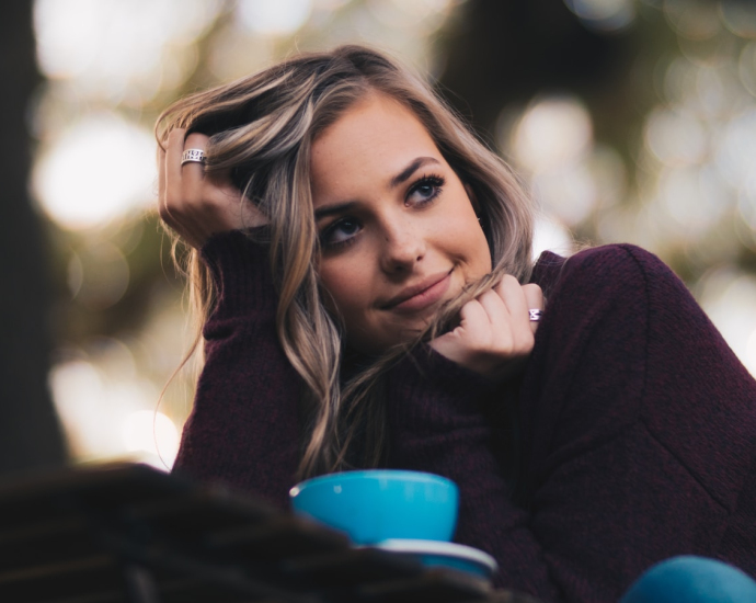 woman in purple long-sleeved top holding her hair