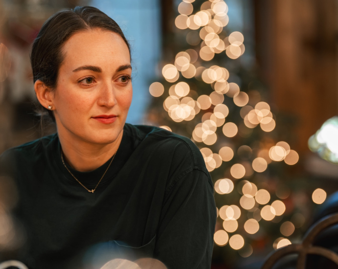 a woman sitting at a table in front of a christmas tree