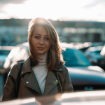 a woman standing in front of a row of parked cars