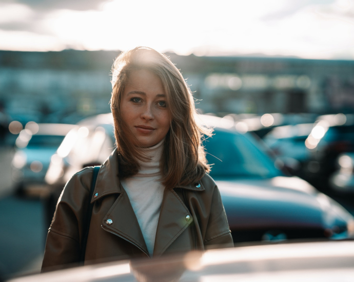 a woman standing in front of a row of parked cars